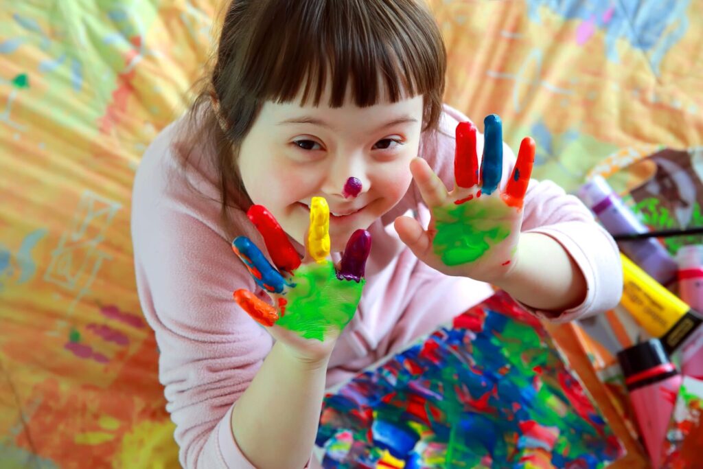 Young child with colorful paint on hands